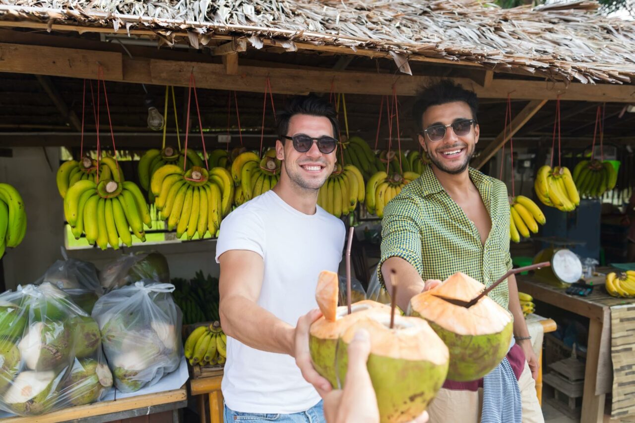 Two men holding coconuts at a local market