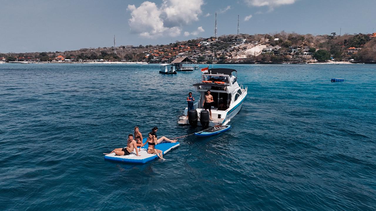 People sitting on an inflatable behind a boat in Bali