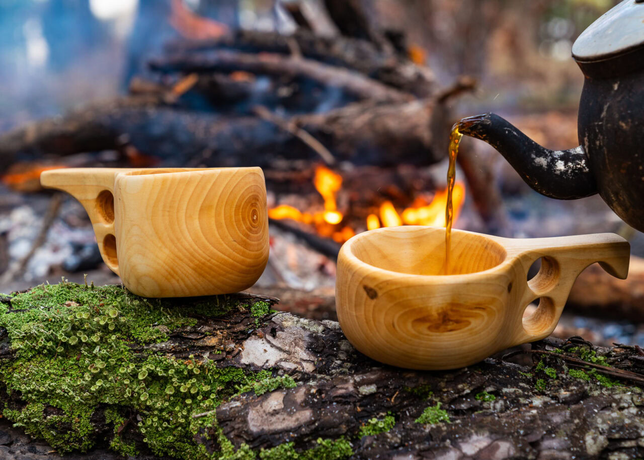 Kuksa wooden much outdoors next to a camp fire in Finland