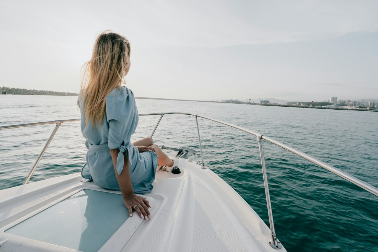 Woman in a blue dress on the front of a yacht