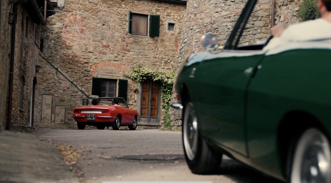 Red and green vintage car parked in a village in Tuscany