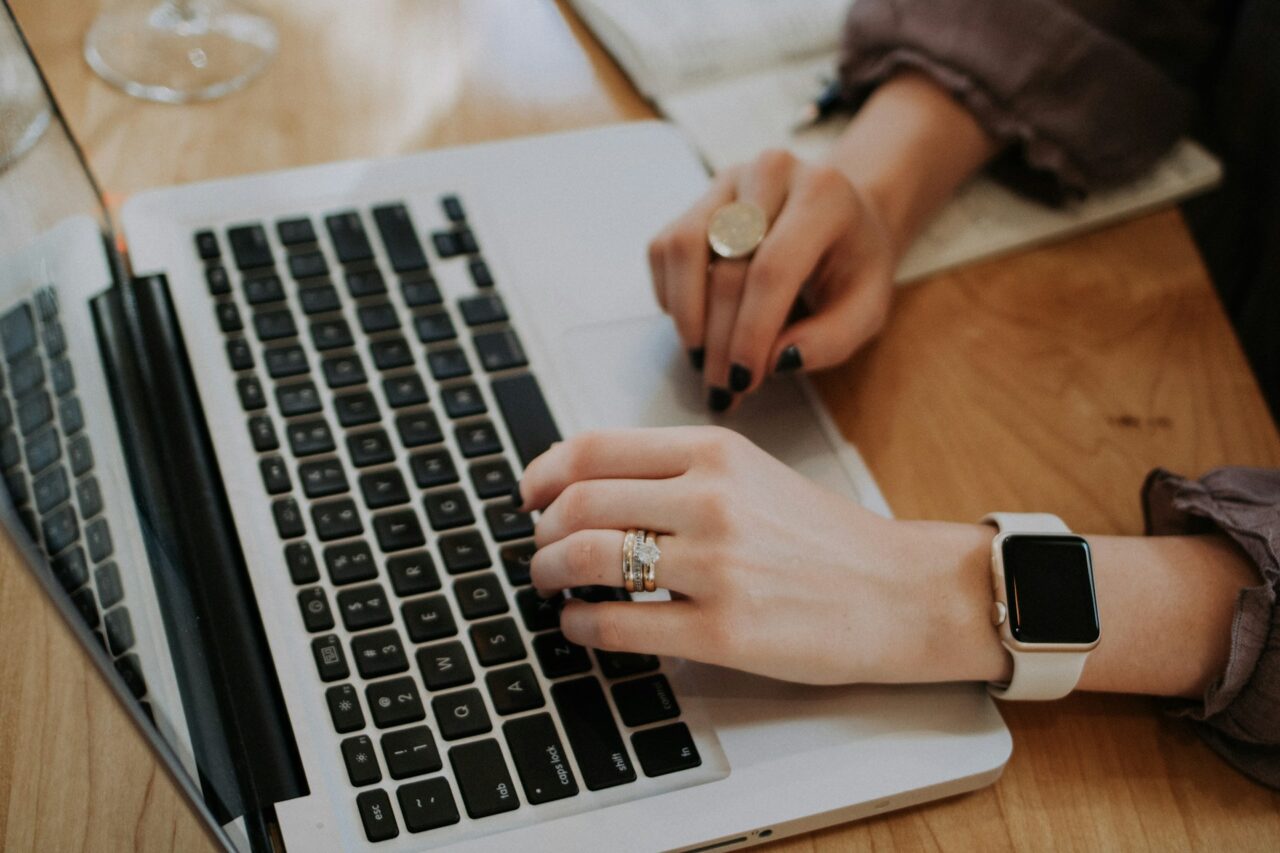 Close up of woman's hands with rings using a laptop