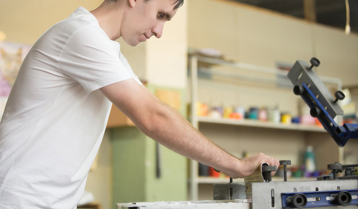 Man operating screen printing press