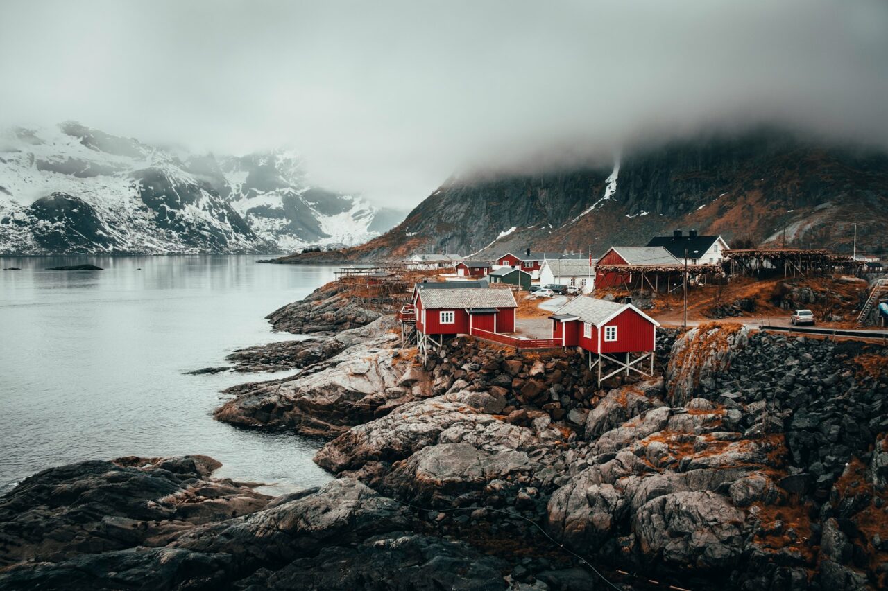 Red buildings on rocks next to a body of water in Norway