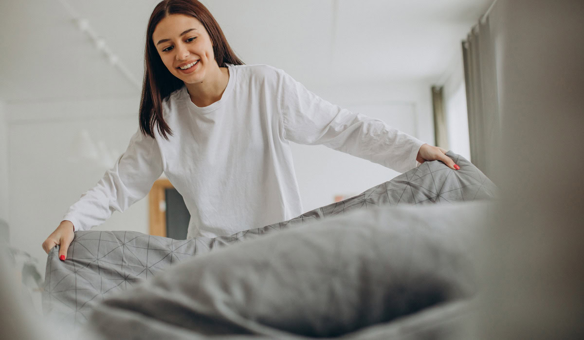 Cheerful woman making bed