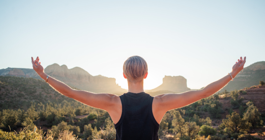 Man raising his arms in the sky in the desert